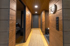 A narrow hallway with wooden walls and a carpeted floor, leading to a door at the end.