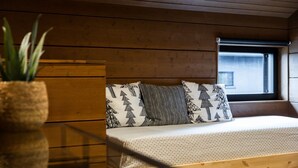 Een houten cabinemeubilair met een bed, kussens, een raam en een plant.