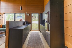 A modern kitchen with a central island, wooden walls, and a view of the outdoors.