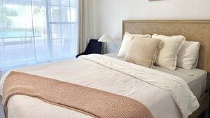 Een hotelkamer met een bed, een stoel, een lamp en een raam met gordijnen.