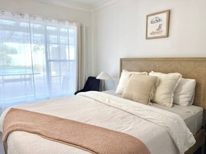 A hotel room with a bed, a chair, a lamp, and a window with curtains. - Mahalo at Anna Bay (Anna Bay)