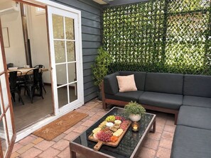 A patio with a glass table, black sofa, and a green plant. - Mahalo at Anna Bay (Anna Bay)