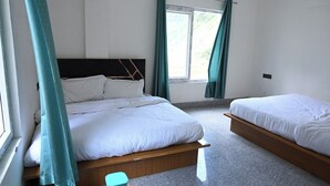 A room with two beds, a window with curtains, and a small table. - Hotel Uday Villa (Rajgarhi)