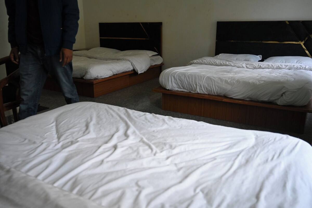 Una habitación de hotel con tres camas, cabeceros de madera y una pared lisa.