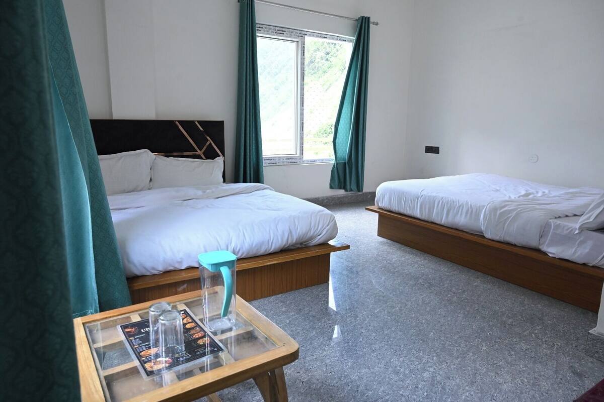 Habitación de hotel con dos camas, una mesita con un menú y una ventana con cortinas.