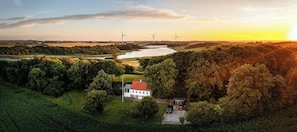 Paisaje rural con una casa, aerogeneradores y un río.