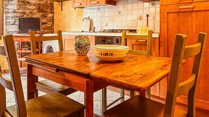 Et køkken med træskabe, en stenvæg, et flisebeklædt backsplash, et træspisebord og stole.