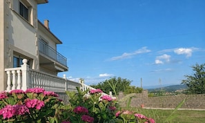 A two-story building with a balcony, surrounded by lush greenery and pink flowers. - Apartment in 1 early 20th century house, five minutes from six beaches. (Suances)