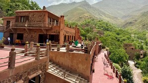 A traditional building with a stone facade, a balcony, and a view of a mountainous landscape.