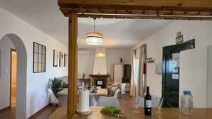 Una cocina moderna con mostrador de madera, una lámpara colgante y una zona de comedor al fondo.