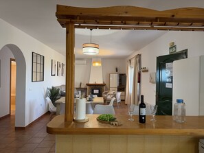 A modern kitchen with a wooden counter, a hanging light fixture, and a dining area in the background. - Cortijo del Verdial by At Home Costa del Sol (Torrox)