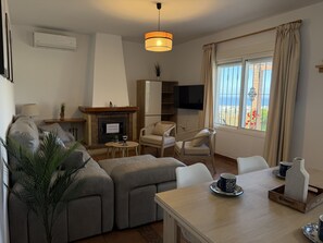 A living room with a sofa set, a fireplace, a television, and a dining area with a table and chairs. - Cortijo del Verdial by At Home Costa del Sol (Torrox)