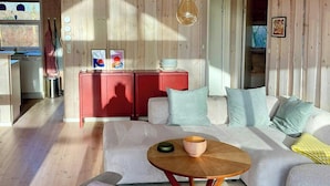 Een gezellig houten interieur met een bank, een eettafel en een keukenhoek.