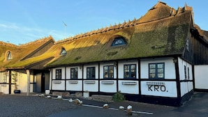 Een traditioneel gebouw met rieten dak en witte muren met zwarte accenten.