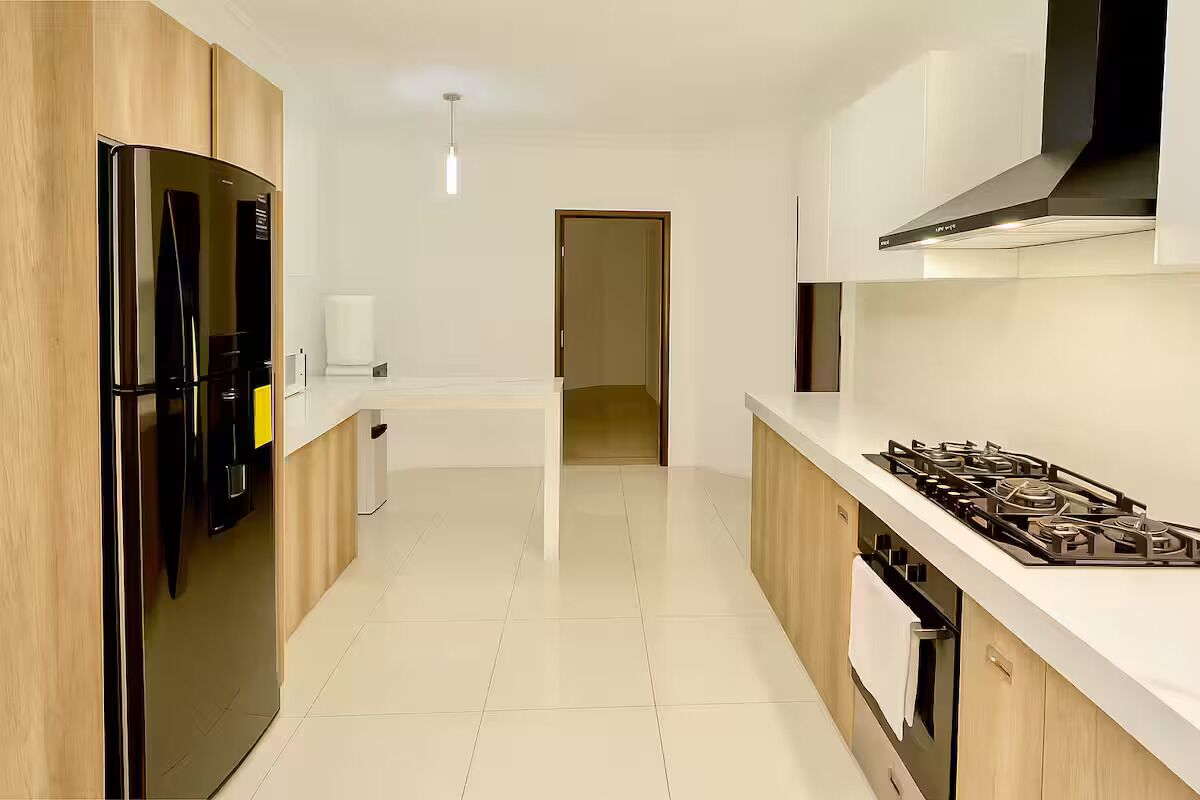 A modern kitchen with a black refrigerator, white countertop, and a gas stove.