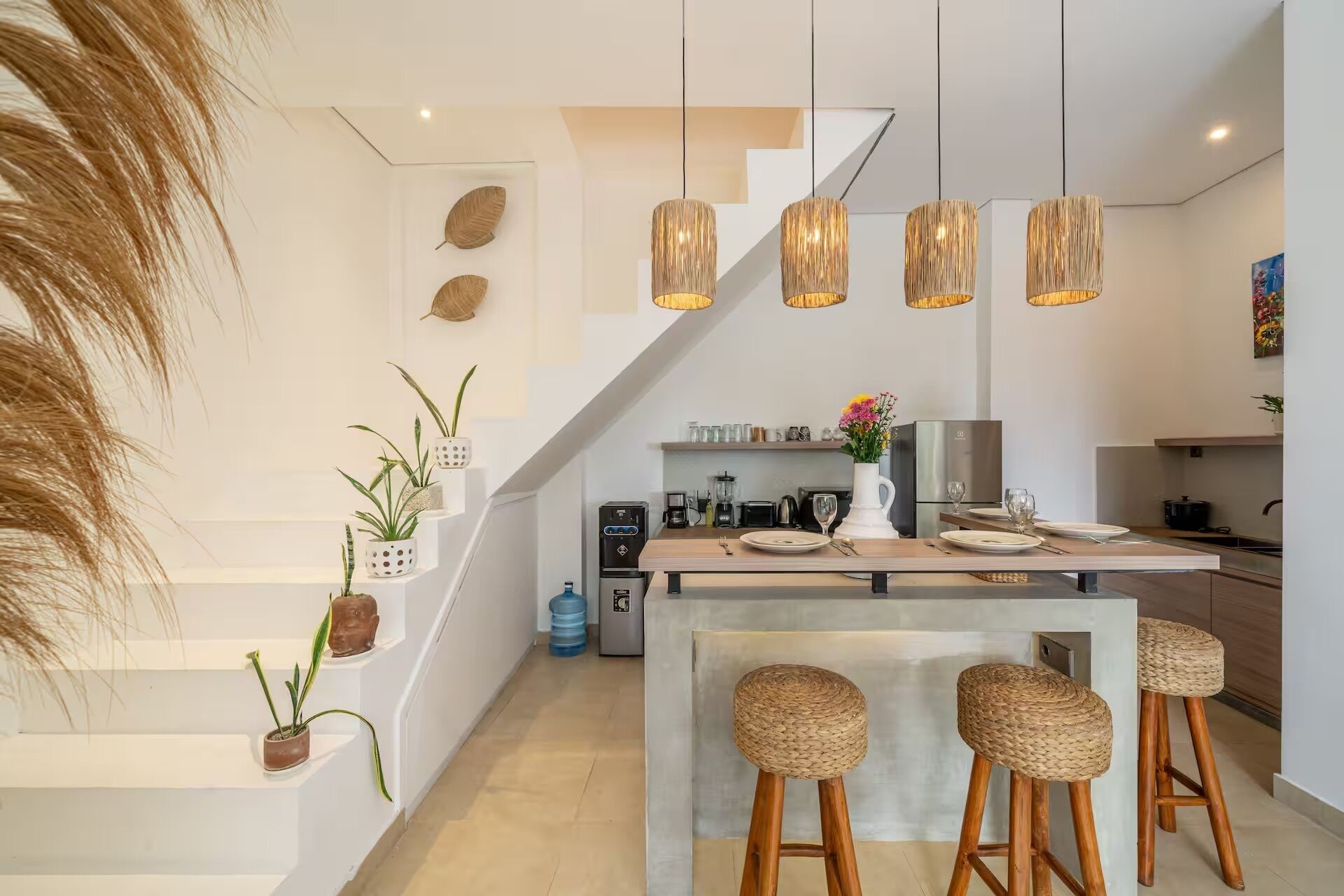 Una cocina moderna con una isla central, taburetes de bar y lámparas colgantes.
