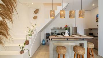 Una cocina moderna con una isla central, taburetes de bar y lámparas colgantes.