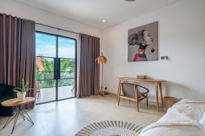 Una sala de estar moderna con un gran ventanal corredera, una lámpara de pie, un cuadro, una mesa de madera y una silla.