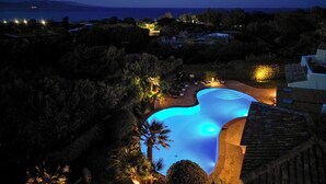 A nighttime view of a resort with a swimming pool, surrounded by trees and buildings. - Villa Flor, Exclusive Property With Pool in Stintino (Stintino)