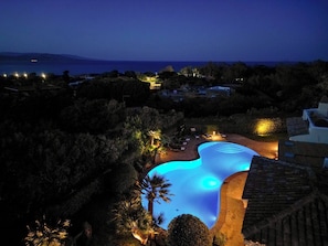 A nighttime view of a resort with a swimming pool, surrounded by trees and buildings. - Villa Flor, Exclusive Property With Pool in Stintino (Stintino)