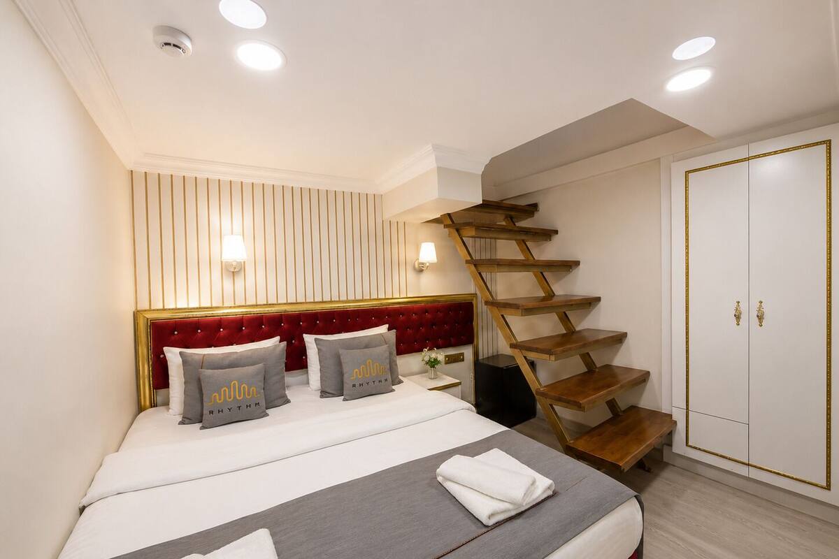 Un dormitorio con una cama, cabecera roja, una escalera de madera y un armario.