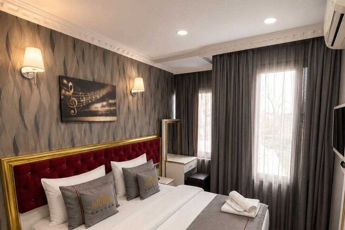 Una habitación de hotel con una cama grande, una mesita de noche, un espejo y una ventana con cortinas.