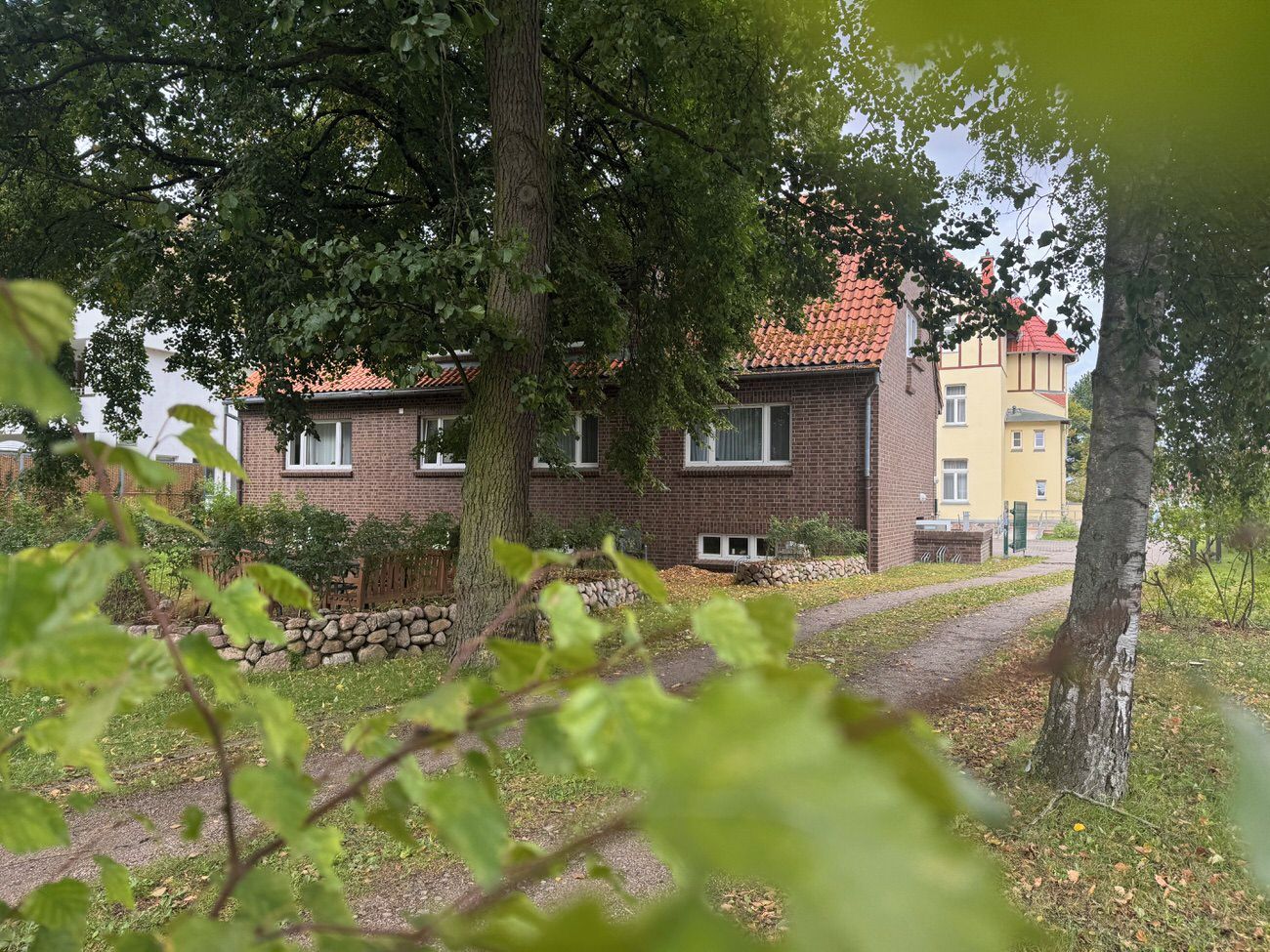 Een woongebouw met een bakstenen gevel, een dak met rode dakpannen en een pad naar de ingang.