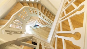 Una escalera espiral blanca con piso de madera que conduce a un nivel superior.