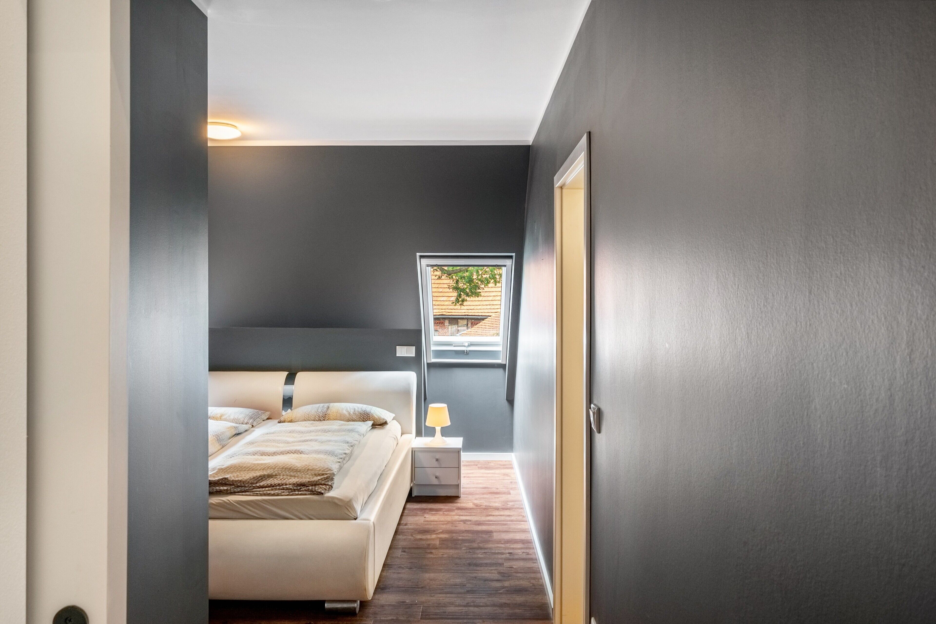 Une chambre à coucher avec un lit, une table de chevet et une fenêtre donnant sur un paysage verdoyant.