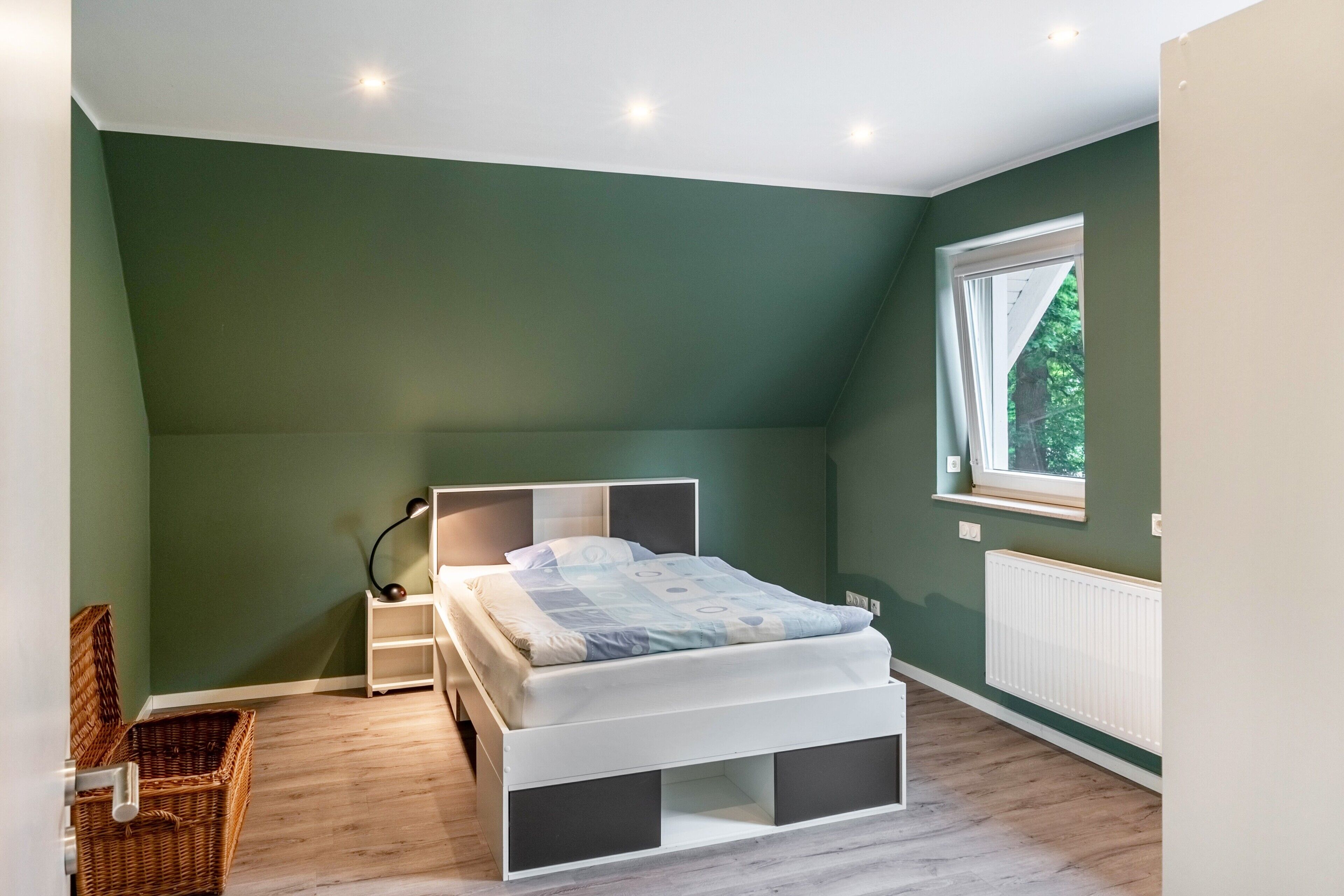 Une chambre à coucher avec un lit, des tables de chevet, une fenêtre et un radiateur.