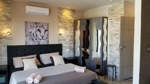 Ein Schlafzimmer mit einem großen Bett, einem Tigergemälde, einem Kleiderschrank und einer Steinwand.