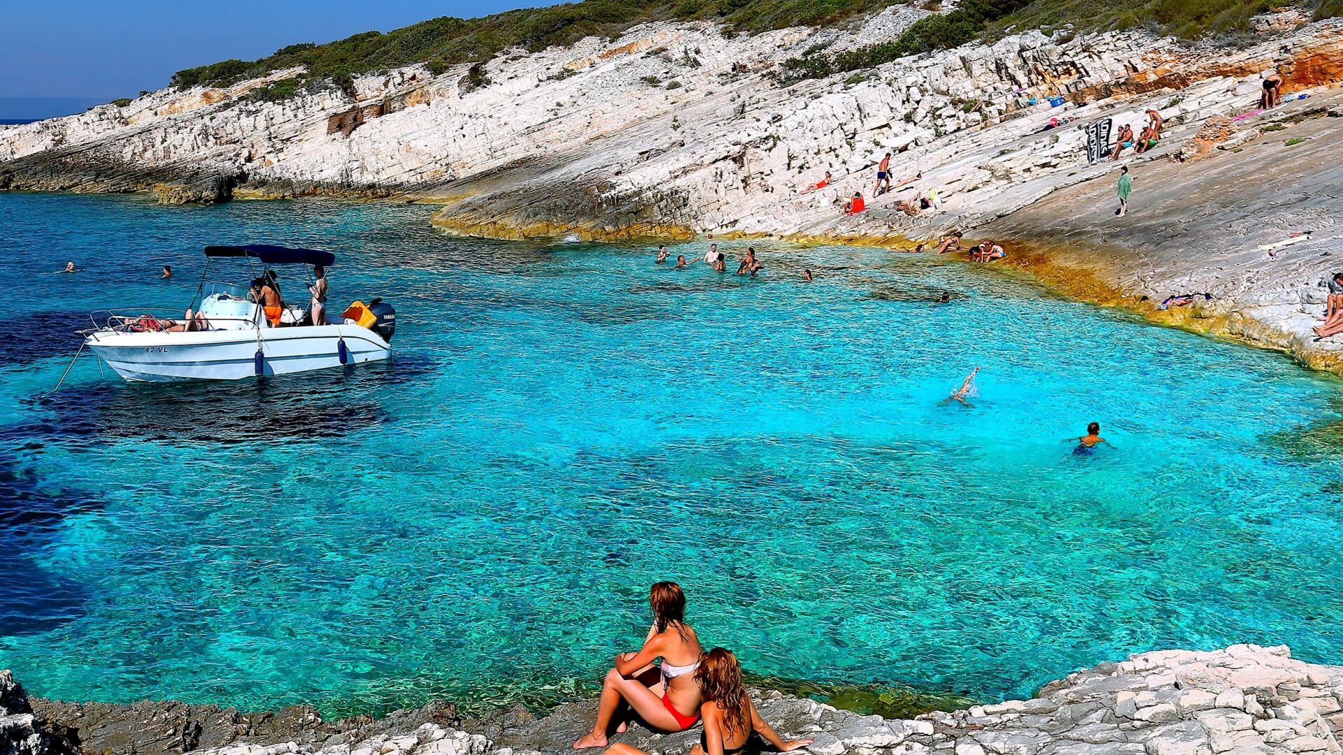 Eine Küstenlandschaft mit klarem türkisblauem Wasser, felsigen Klippen und einem Boot.