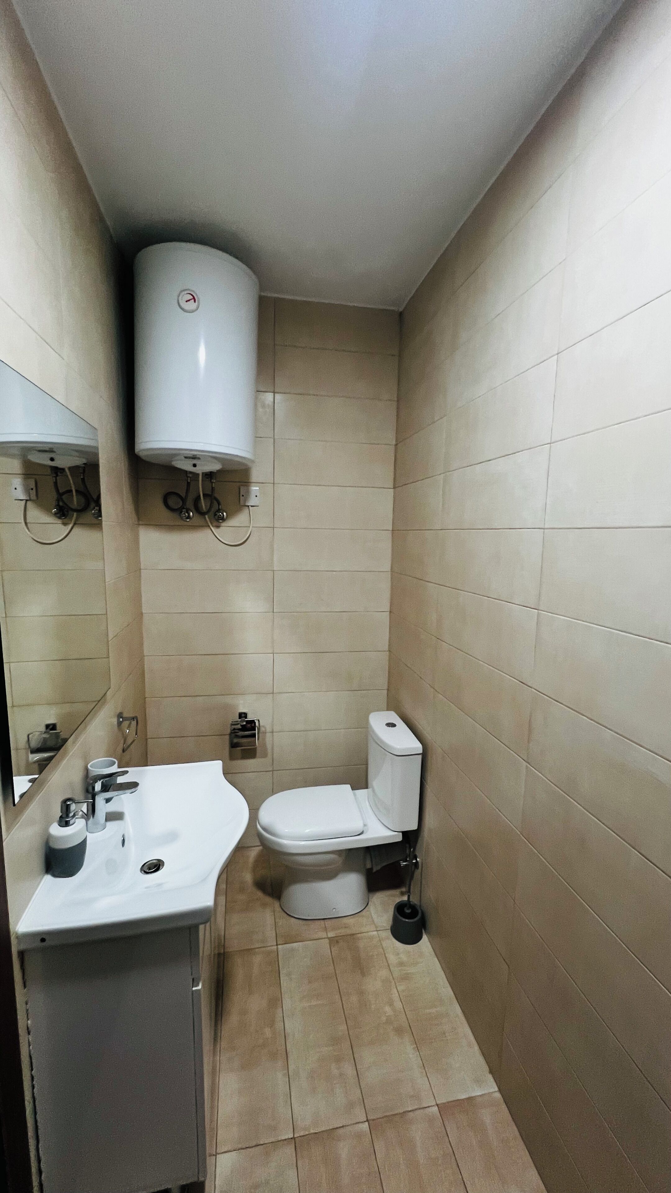 A small, clean bathroom with a toilet, sink, and mirror.