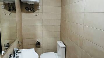 A small, clean bathroom with a toilet, sink, and mirror.