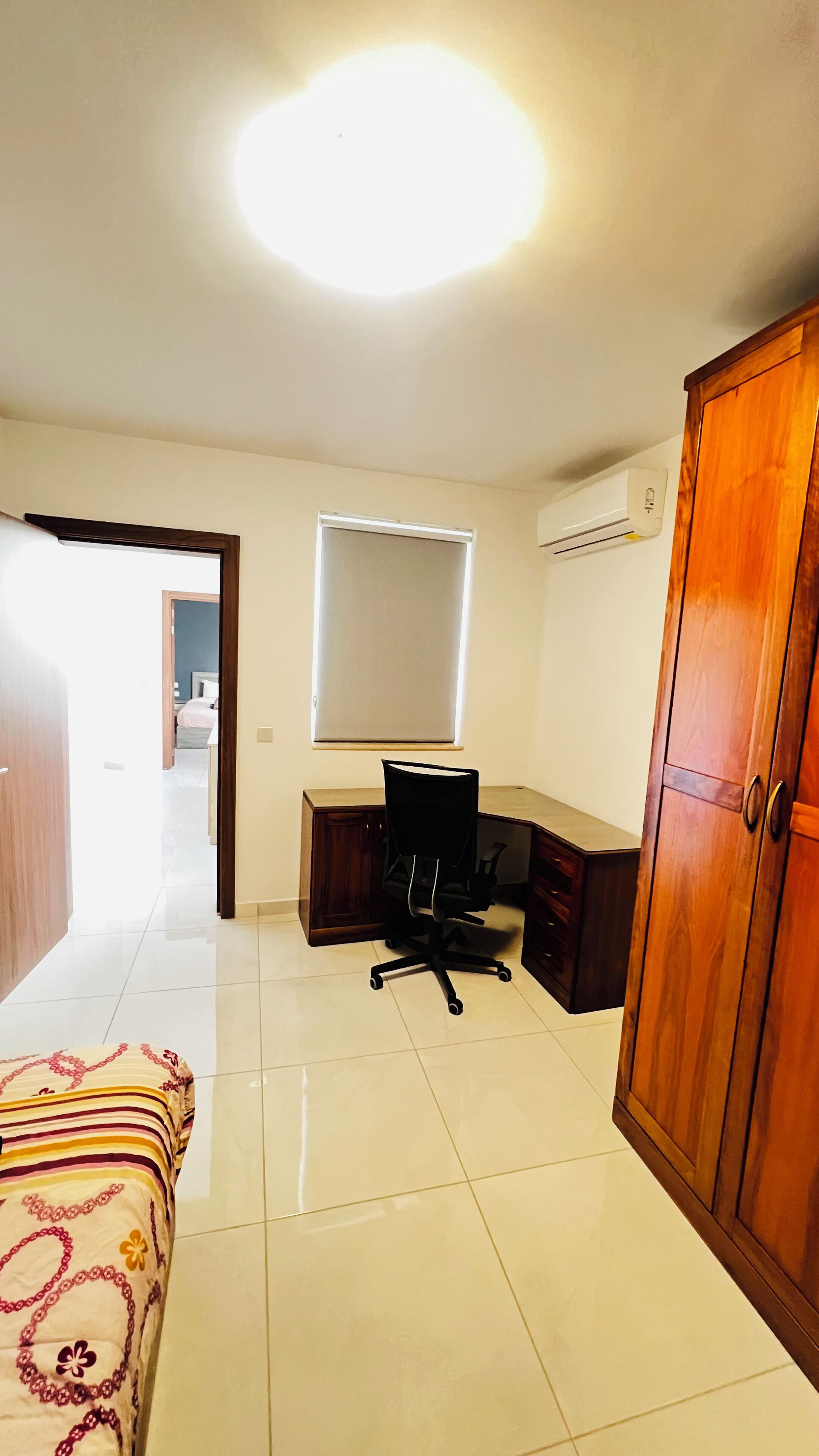 Une chambre à coucher comprenant un lit, un bureau, une chaise, un climatiseur et une armoire.