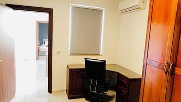 Une chambre à coucher comprenant un lit, un bureau, une chaise, un climatiseur et une armoire.