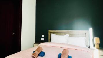A hotel room with a bed, a wooden headboard, a nightstand, and a wall-mounted light fixture.