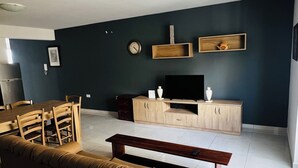 Ein Wohnzimmer mit Sofa, Fernsehtisch und Essbereich.
