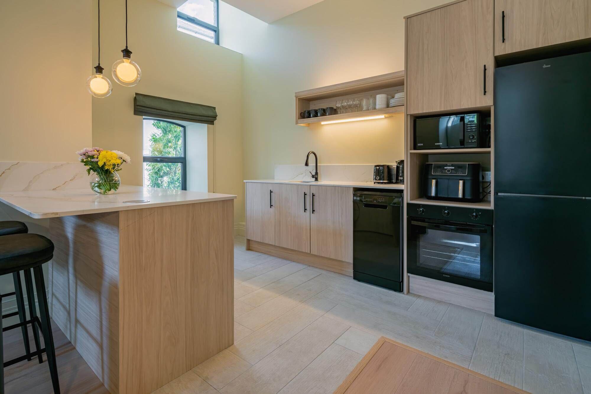 A modern kitchen with a central island, built-in appliances, and a window providing natural light.