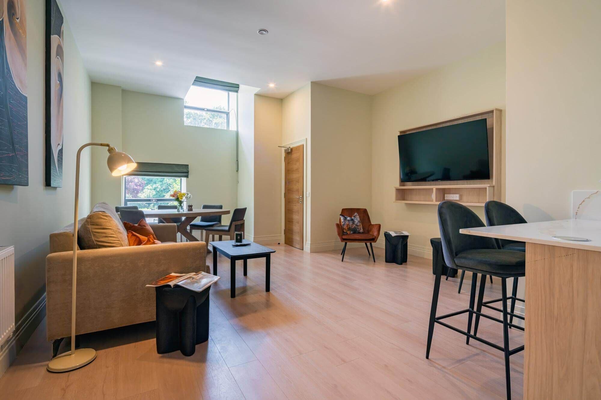 A modern living room with a sofa, coffee table, TV, and dining area.