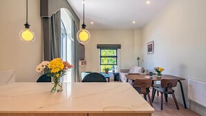 Una cocina moderna con encimera de mármol, armarios de madera e iluminación colgante.