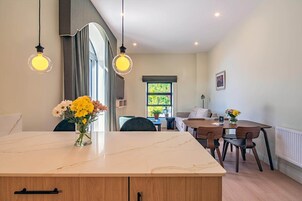 Una cocina moderna con encimera de mármol, armarios de madera e iluminación colgante.