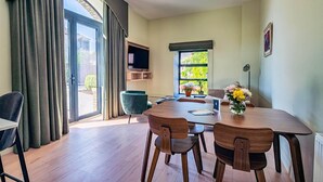 Un comedor con mesa, sillas, televisor y ventana con vista a vegetación.