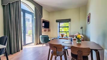 A dining area with a table, chairs, a TV, and a window with a view of greenery.
