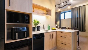 Una cocina compacta con lavavajillas, cafetera y una planta.
