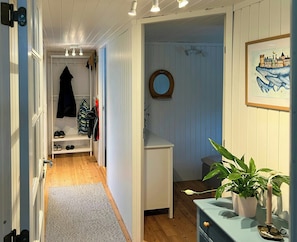A hallway with a wooden floor, a coat rack, a mirror, a framed picture, and a potted plant. - Summer house 344 steps from beach near Saksild (Odder)