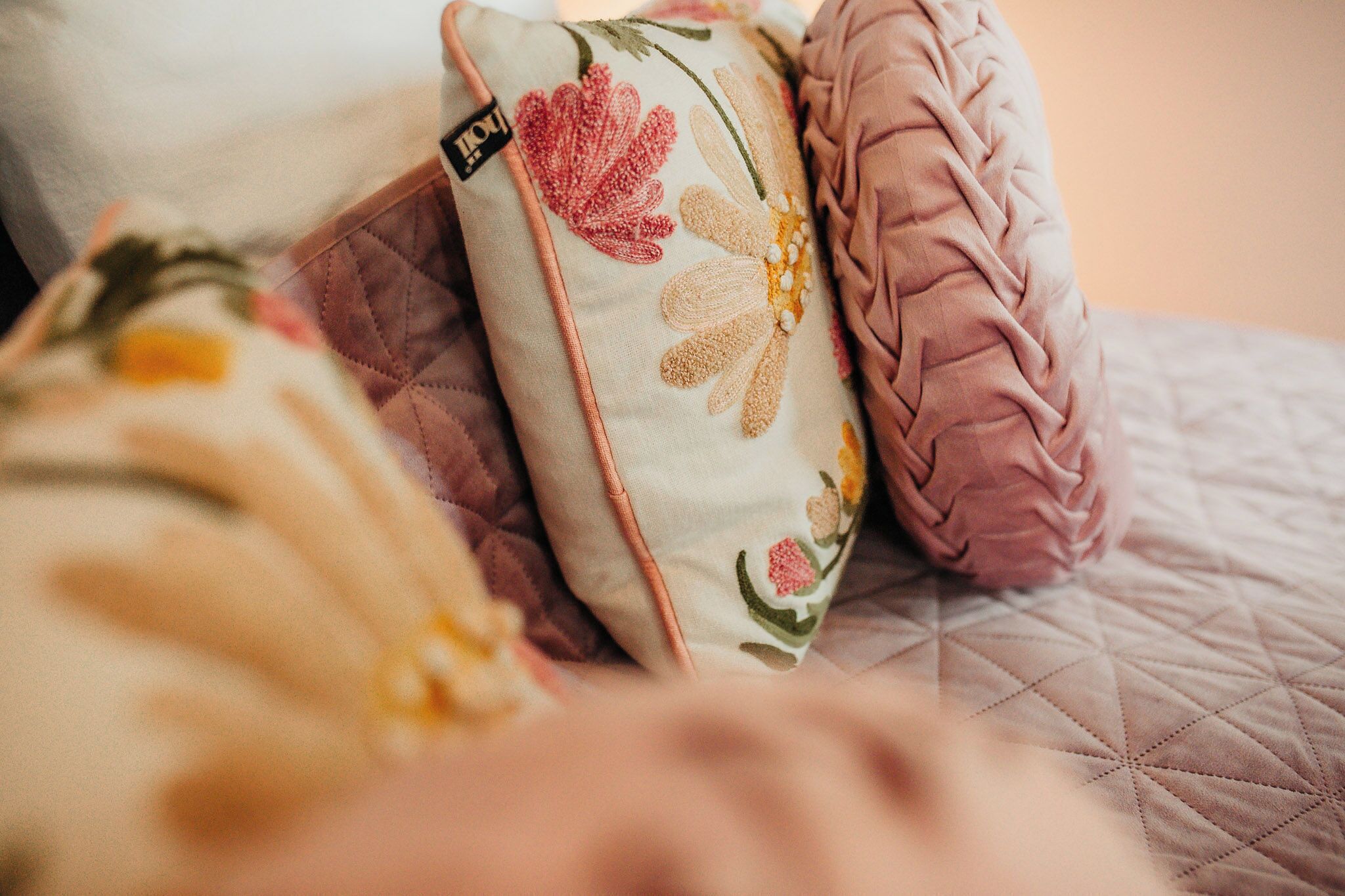 Un gros plan d’un lit avec une couverture matelassée et des coussins décoratifs.