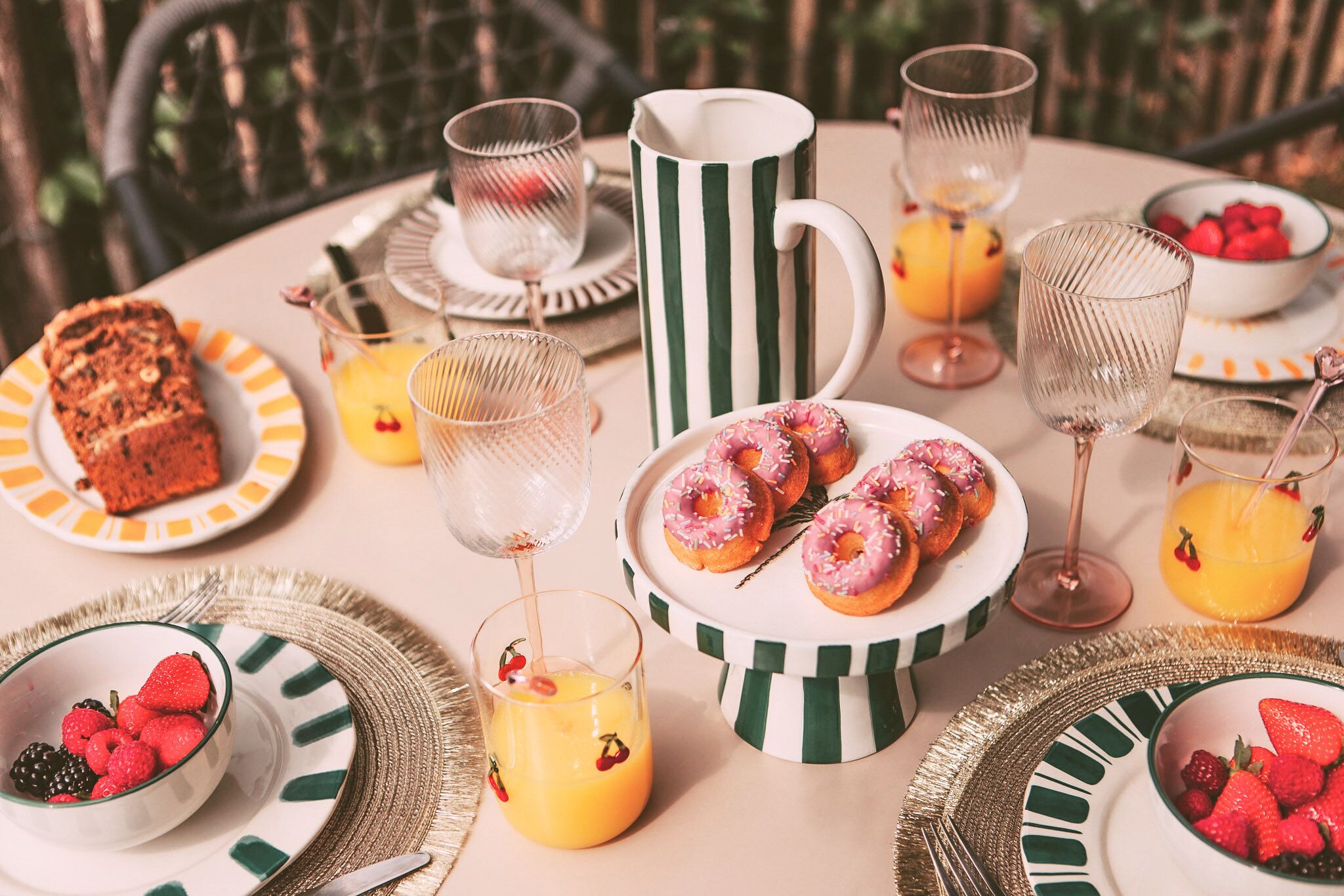 A table set with plates of food, glasses, and a pitcher.