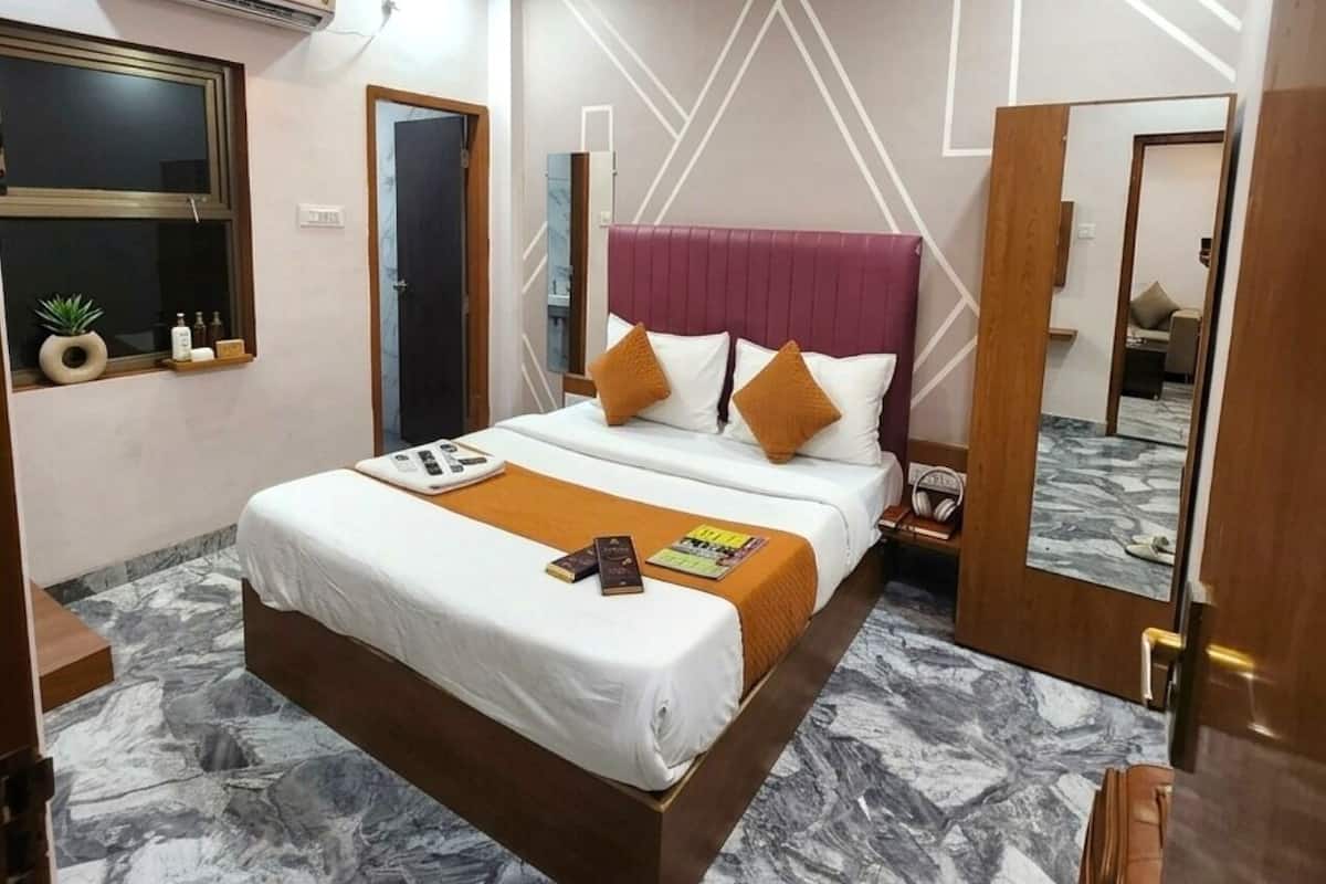 Moderni hotellihuone, jossa on sänky, kattotuuletin, ilmastointilaite ja marmorikuvioitu lattia.