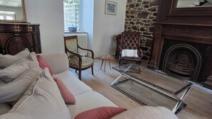 Una sala de estar con un sofá, sillas, una chimenea y una pared de piedra.